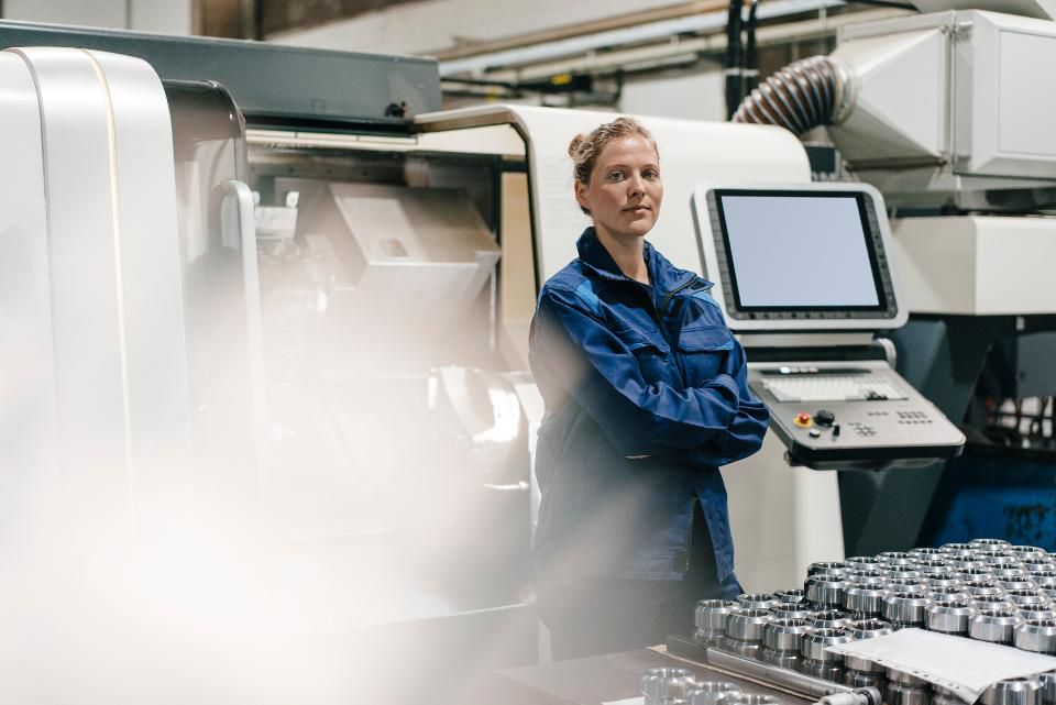 a female factory worker standing in front of machinery