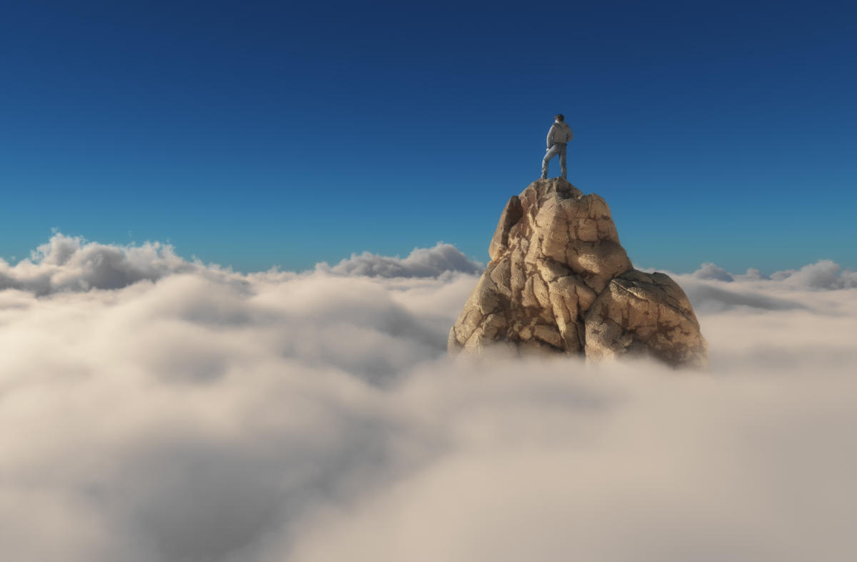 person standing on top of mountain above clouds