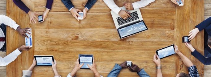 a group of people checking documents through different devices: computer, phone and tablet