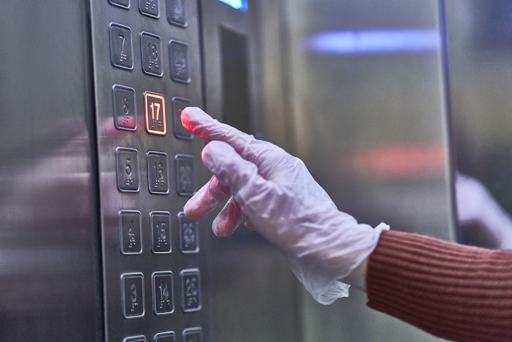 gloved hand touching elevator button
